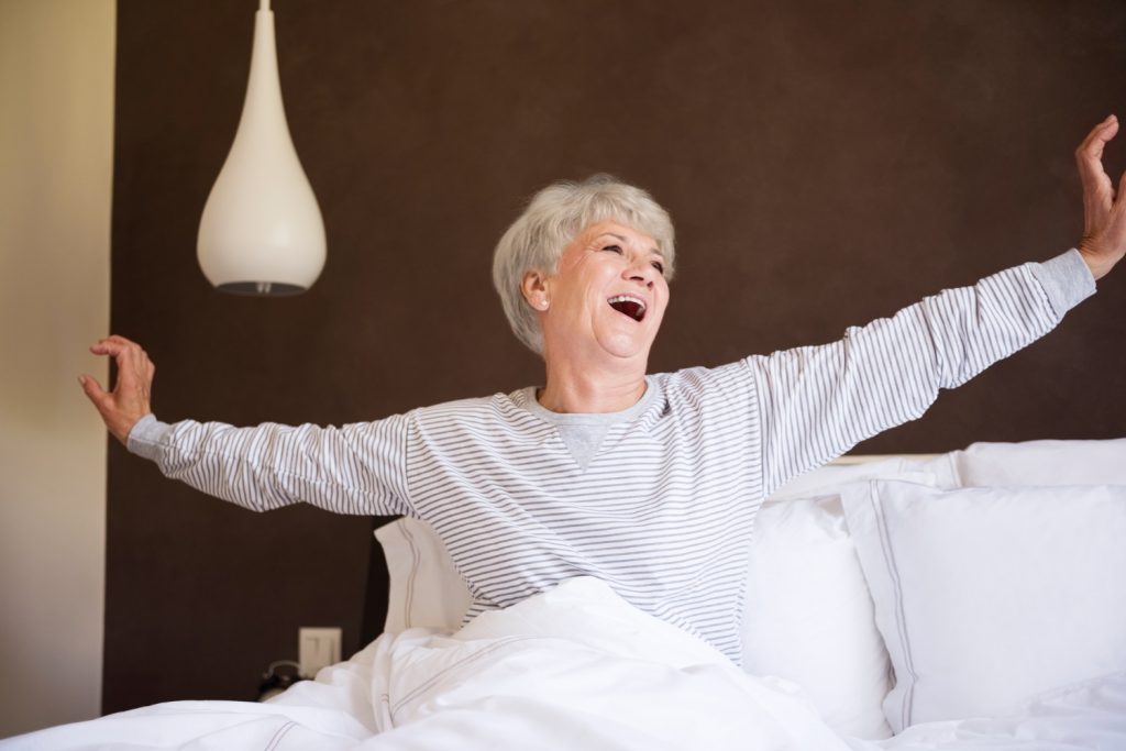 Elderly woman stretching in bed.