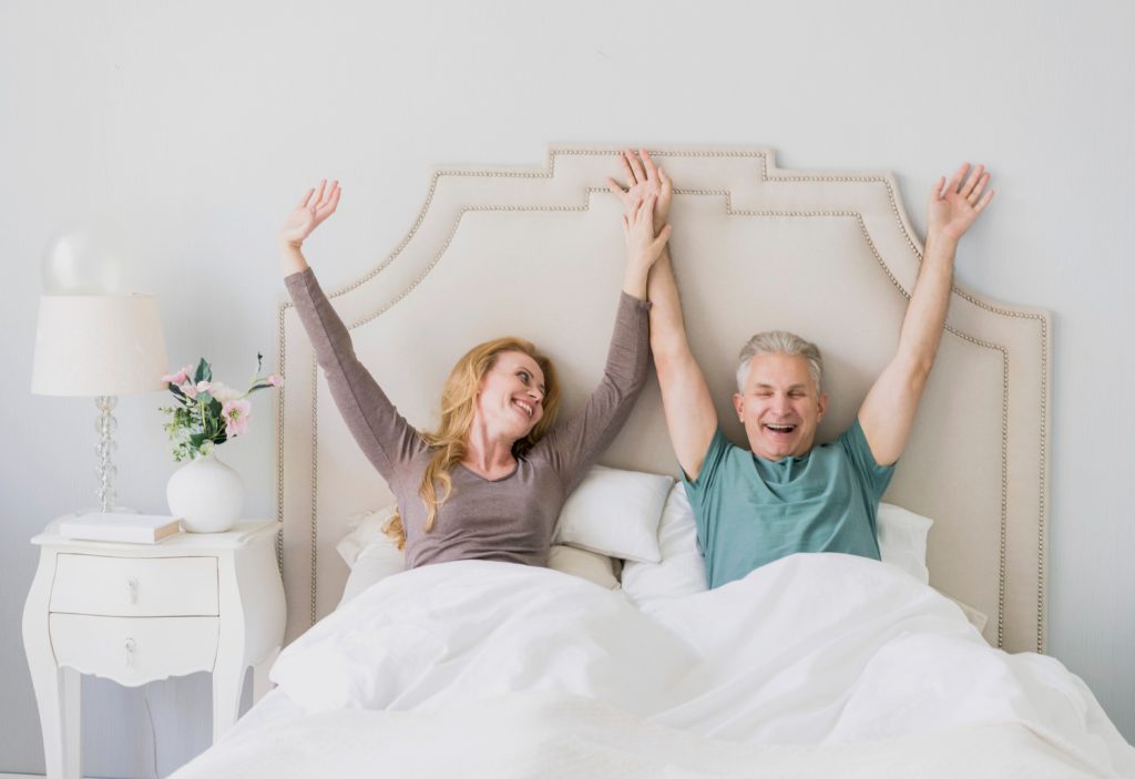 Couple stretching in a bright bedroom.